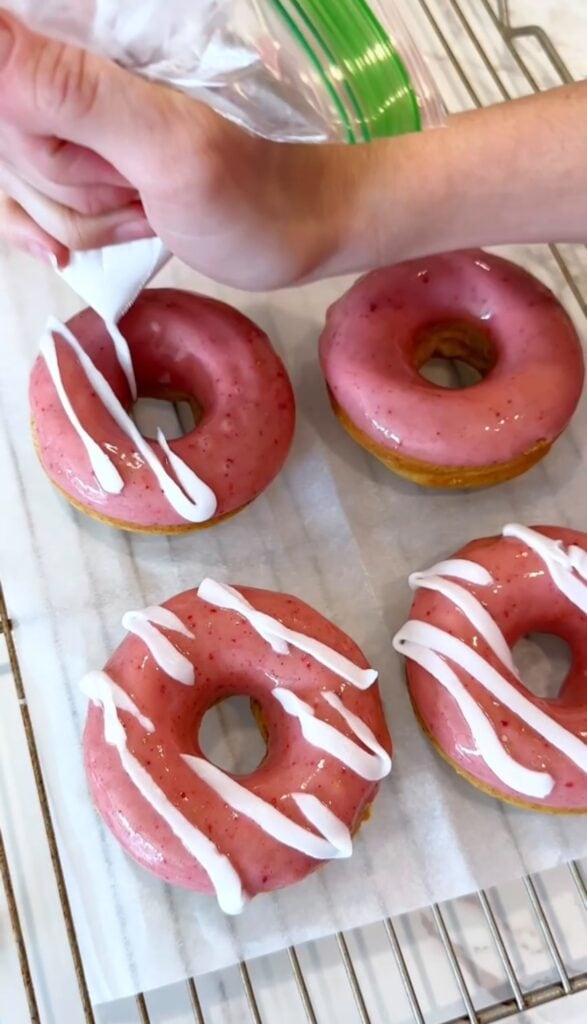 adding dairy free cream drizzle to gluten free strawberry donuts