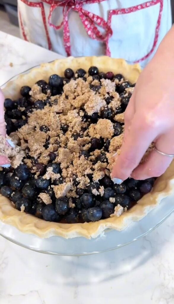 adding gluten free crumble topping to gluten free blueberry crumble pie