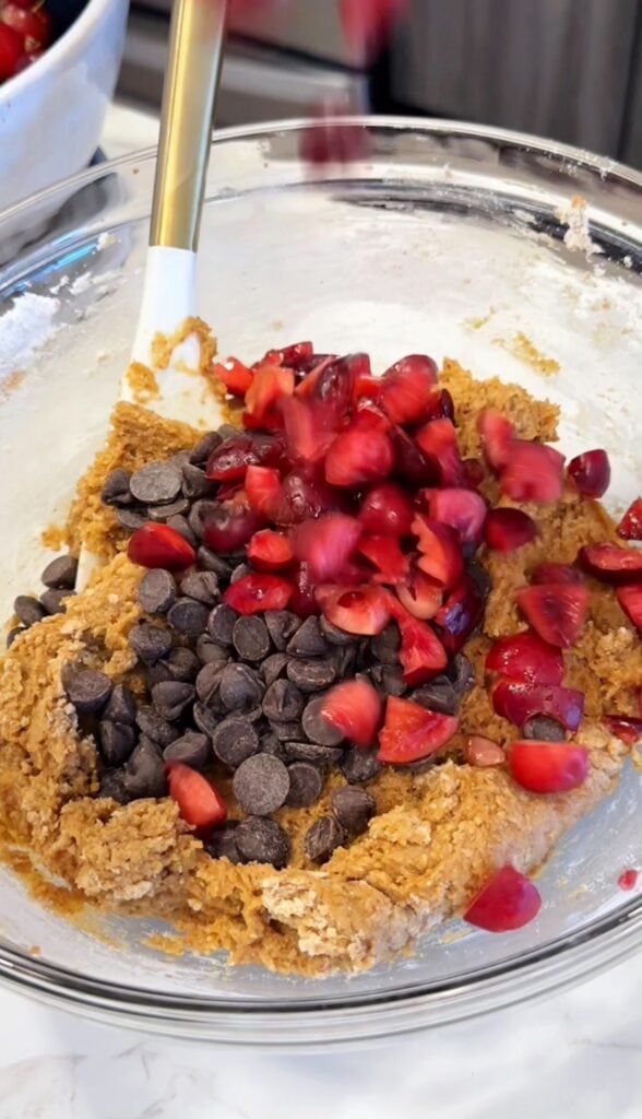 folding in chocolate chips and fresh cherries to gluten free cookie dough batter