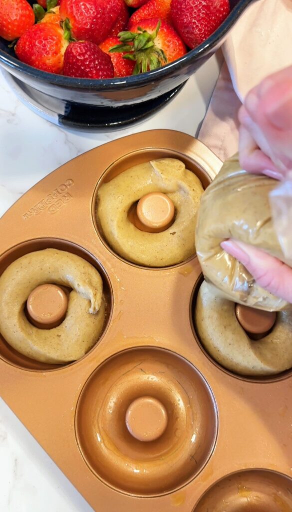 piping gluten free donut batter into donut pan