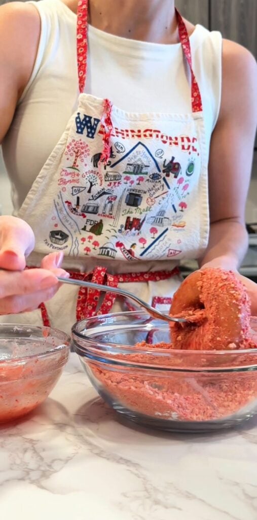 dipping gluten free donuts in strawberry crunch topping